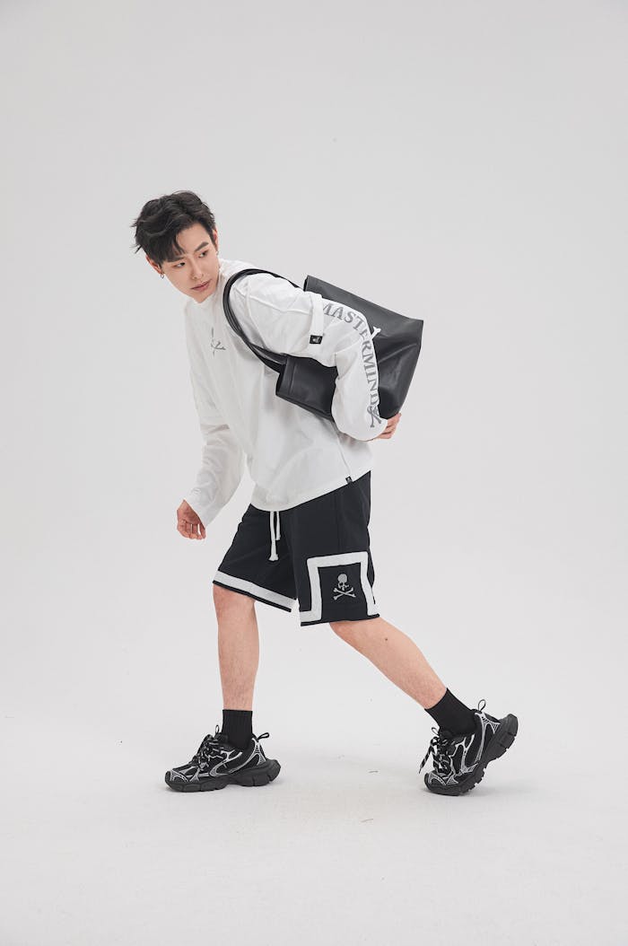 Trendy young adult in sporty attire with a leather tote showcasing casual urban style.