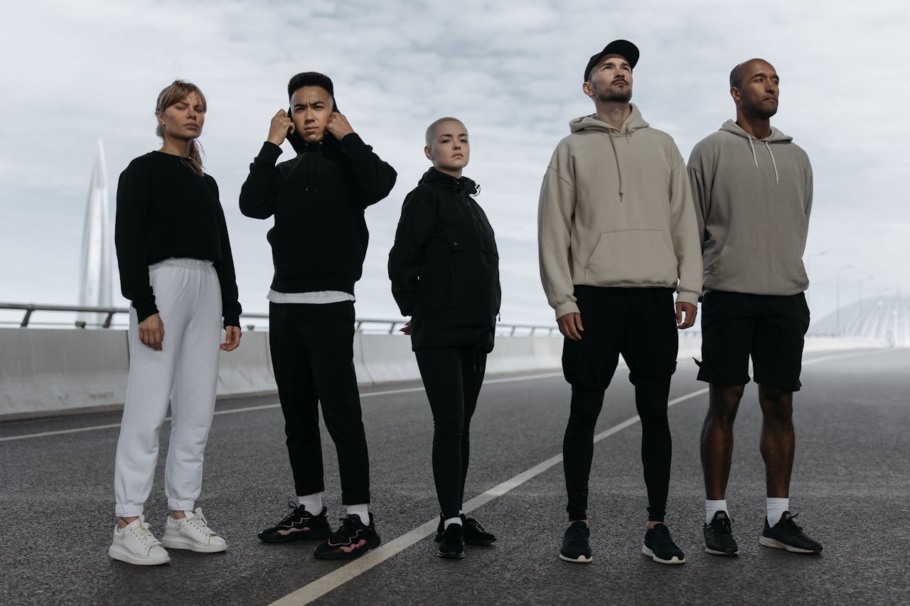 A diverse group of young adults in activewear standing confidently on a road, showcasing modern sports fashion.